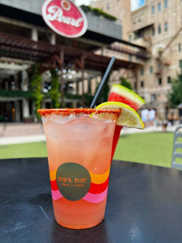 Pink drink with lime in front of Pearl building