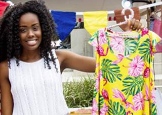 Woman holding a hanger with a yellow shirt.