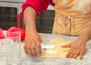 Dough being rolled using a drinking glass