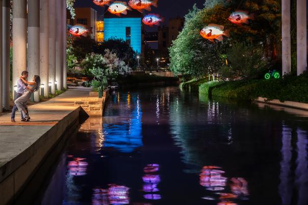 Man dancing with woman on River Walk next to F.I.S.H. exhibit.